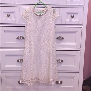 This a white dress with pearls on the neck.